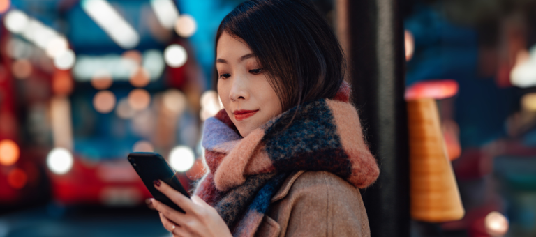 Women next to London bus stop looking at phone at night