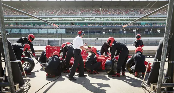 Pit crew replacing tires on race car