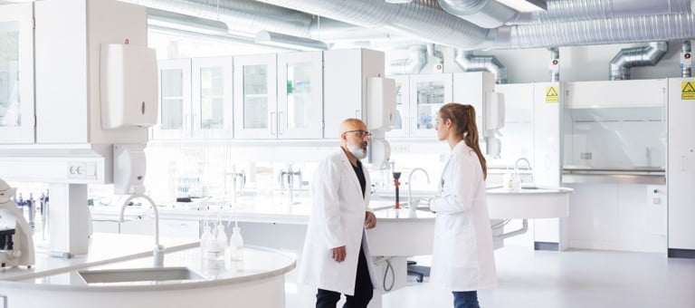 Two scientists in conversation, standing in laboratory