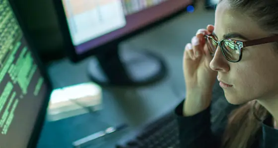 A woman with glasses looking at a computer screen