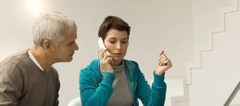Two people looking at bills and calling on the phone