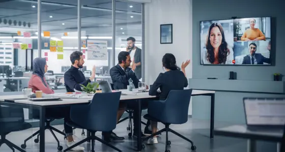 Four people in an office having a virtual meeting with three colleagues