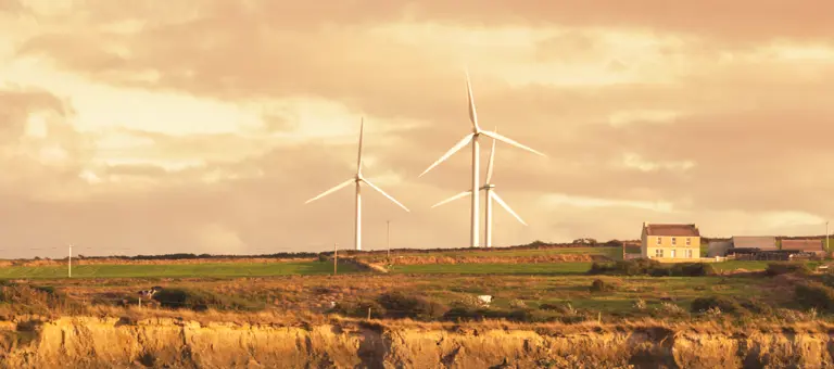 A rural scene with a farmhouse and three wind turbines
