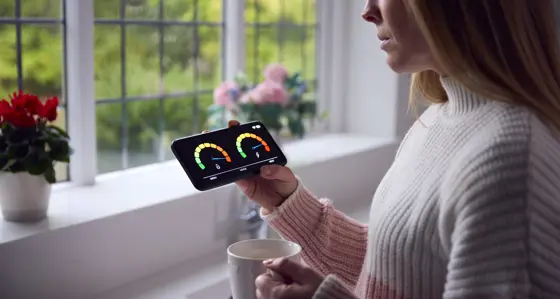 A woman standing in her home looking at a smart meter