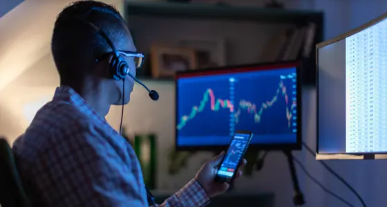 Man looking at charts on his phone and computer