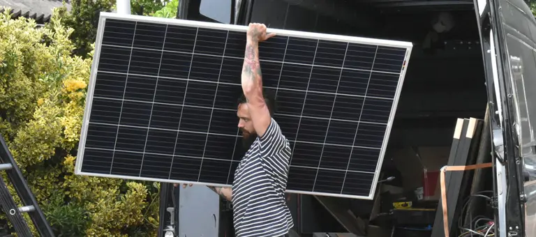 A man taking a solar panel out of a van