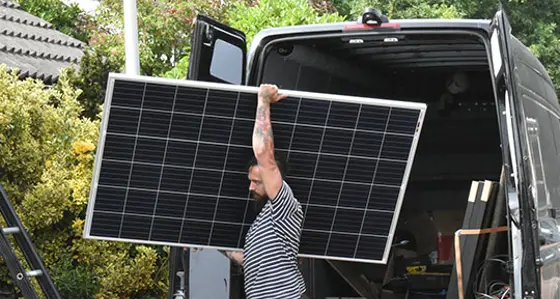 A man taking a solar panel out of a van