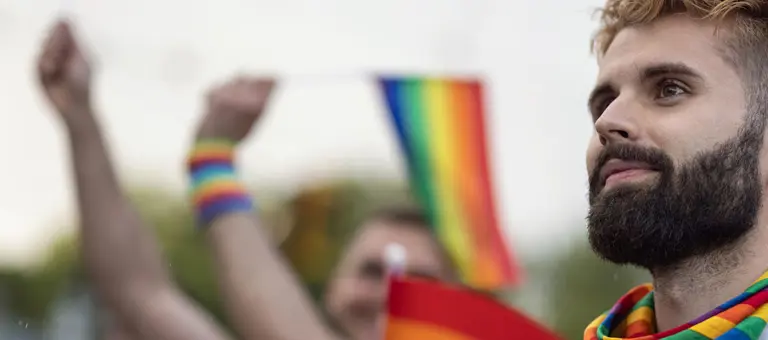 A man in a crowd wearing a rainbow-coloured scarf