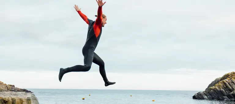A person jumping from a harbour wall into the sea
