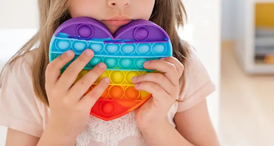 Child holding a rainbow coloured heart