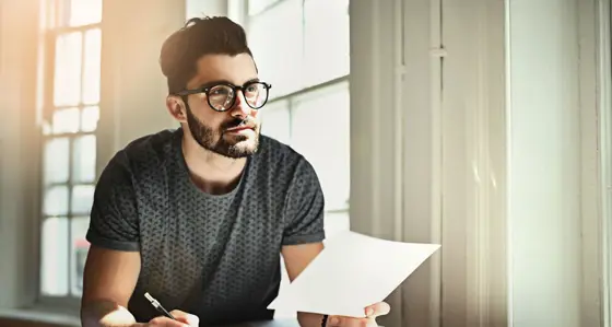 A man working at his desk with pen, paper and tablet