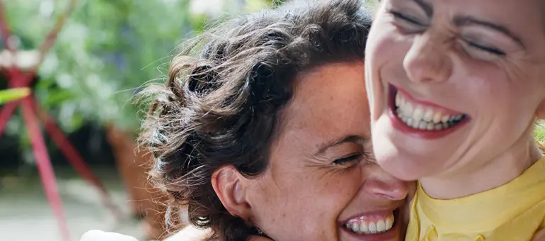 Two happy women smiling and hugging
