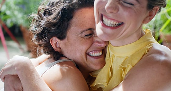Two happy women smiling and hugging