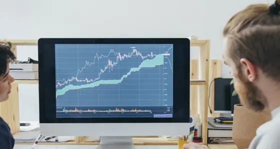 Two people looking at graphs on a computer screen