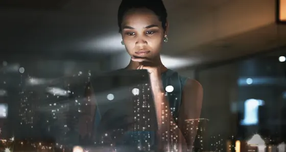 Woman looking at data on a tablet with overlay of city skyline