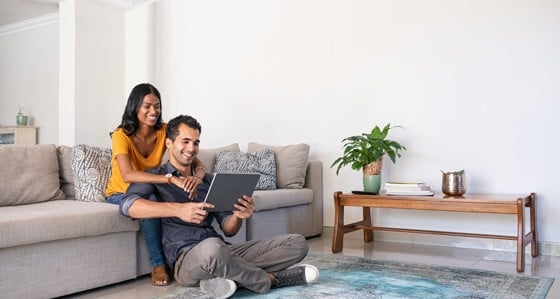 Couple sitting on couch looking at tablet